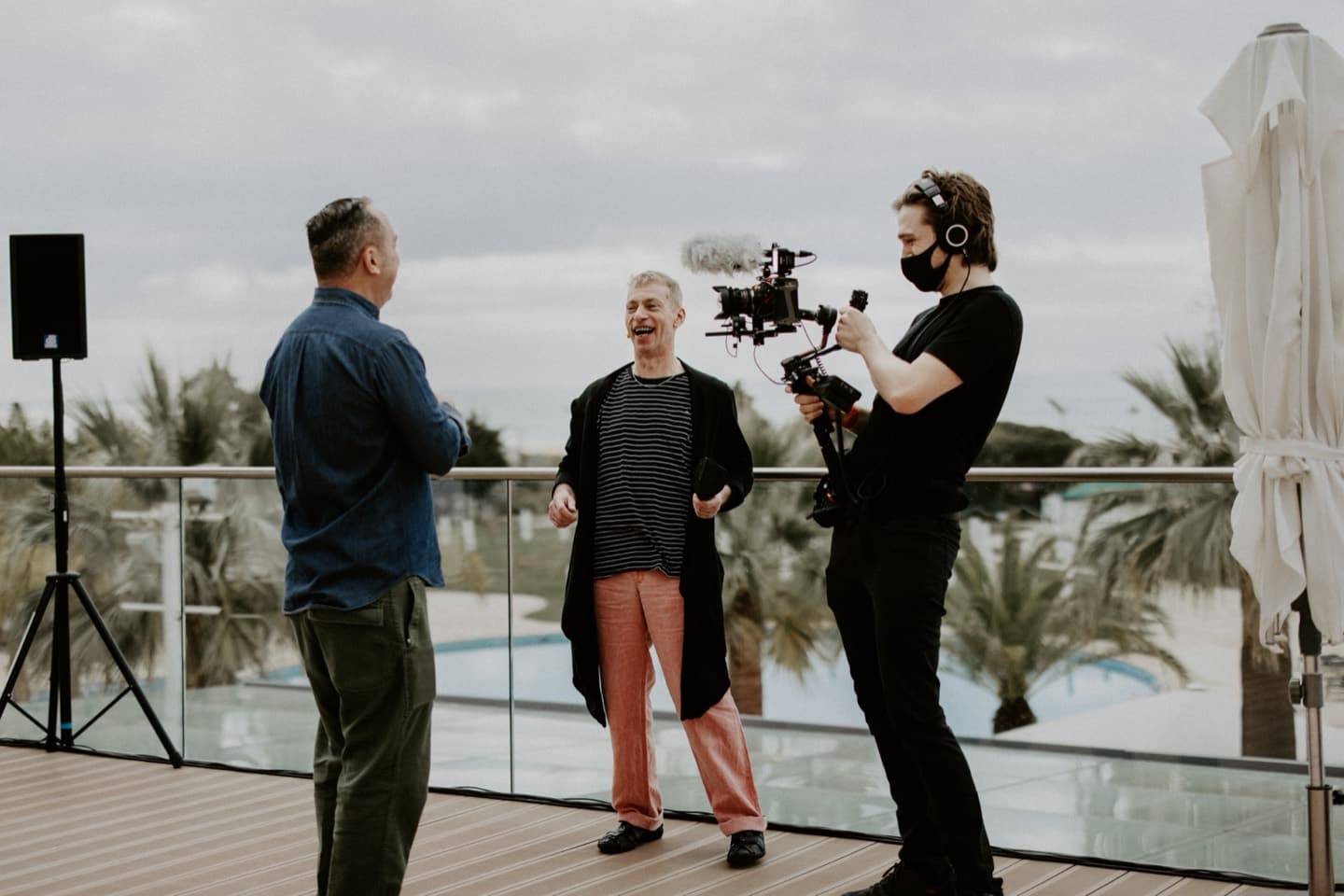 Filming two guests on the terrace, palms and the coast behind them