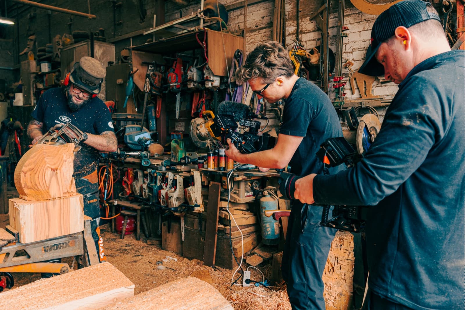 Filming a woodworker at the bench, two of the crew in close with a rigged camera among the tools