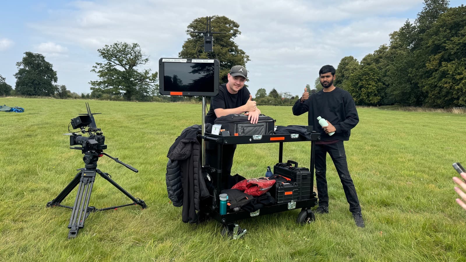 Two of the crew in an open field with the kit cart loaded, camera and monitor already up