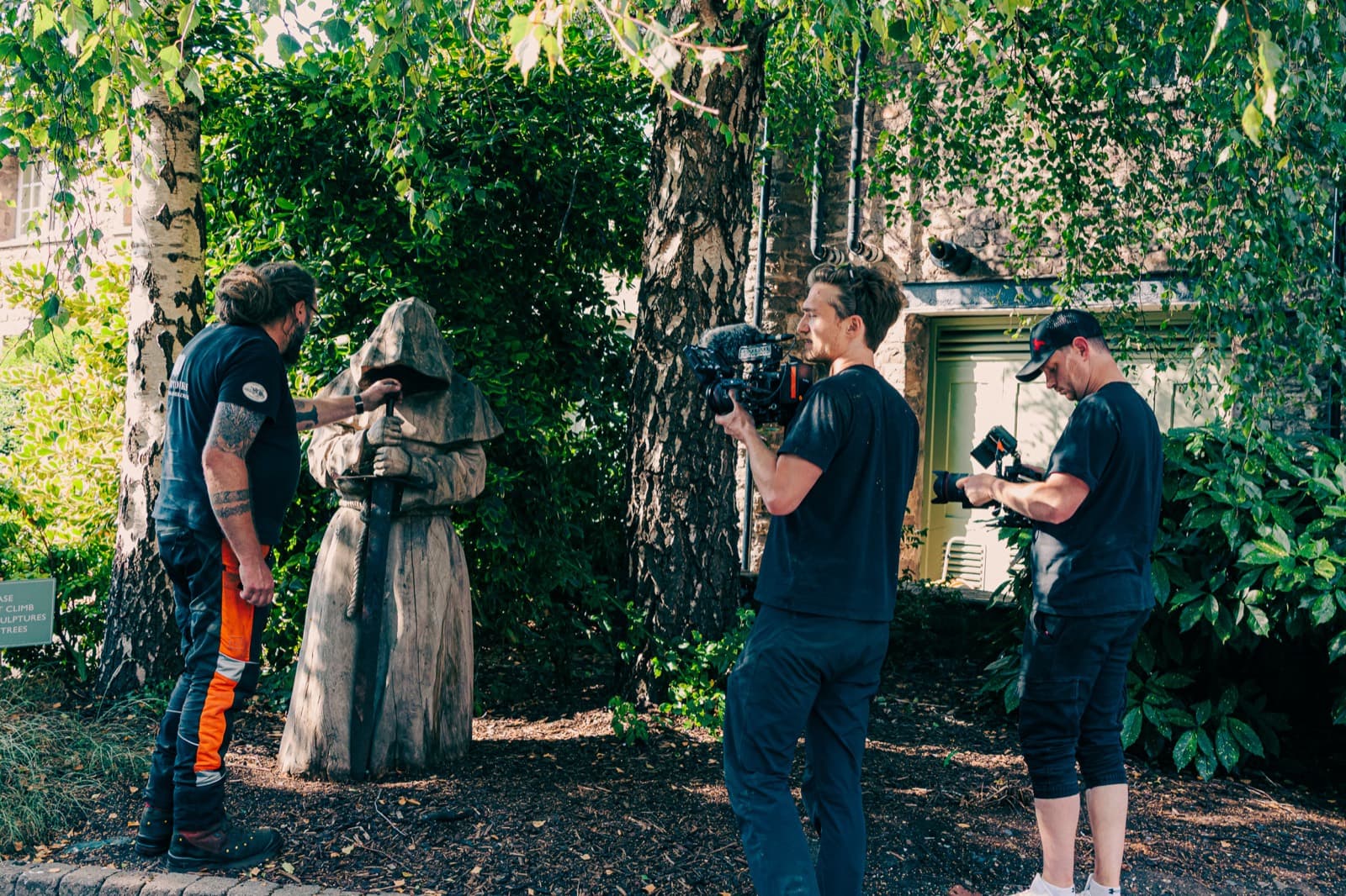 Jack Hobbs and Ben Roberts on two cameras, covering a chainsaw carver beside a finished wooden figure