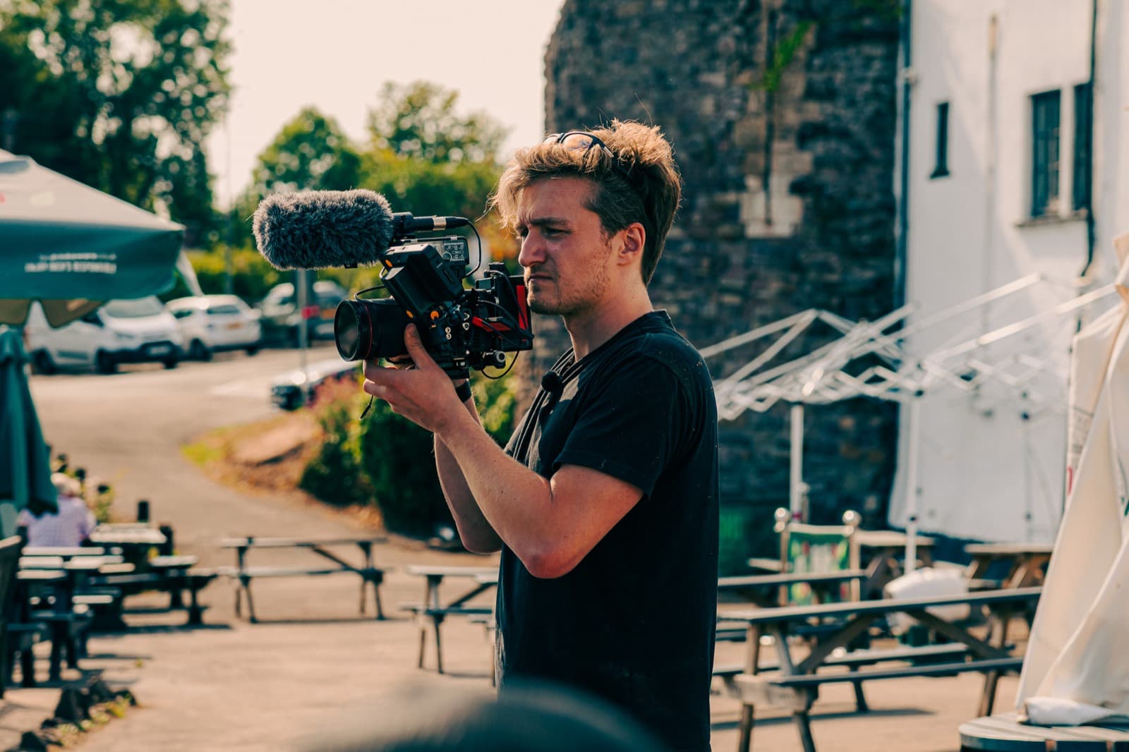 Jack Hobbs shoulder-mounted with a shotgun mic, filming in a pub yard in low sun