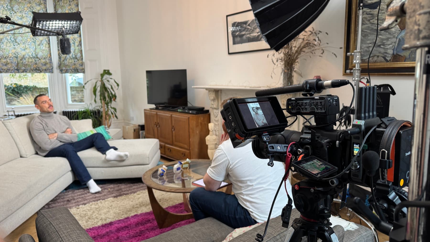 An interview lit in a Victorian sitting room, camera and monitor built up in the foreground, a second head over the window