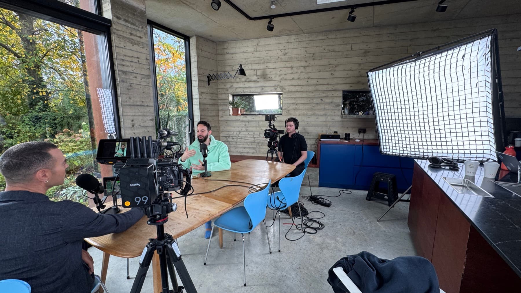 The same set-up wider: a large gridded softbox to the right, camera and monitor on sticks, sound rigged on the table