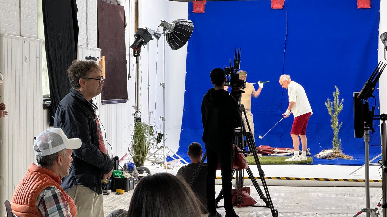 A blue screen dressed with artificial turf and plants for a golf sequence, camera locked off and the client watching from behind it
