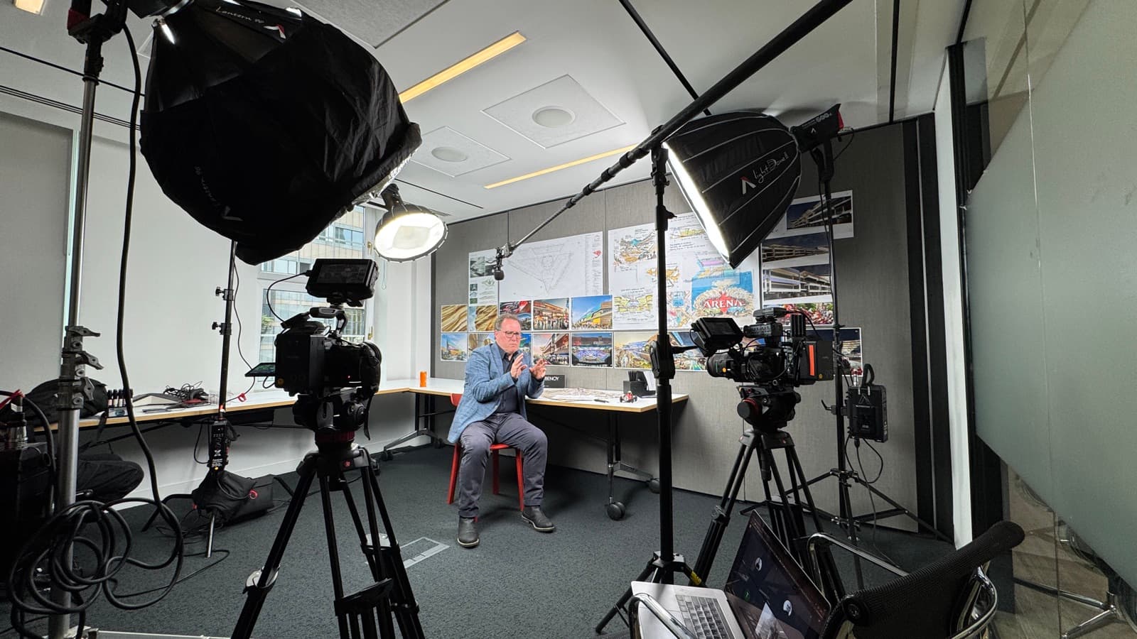 An office turned into an interview set, two large softboxes and two cameras on a contributor at a desk