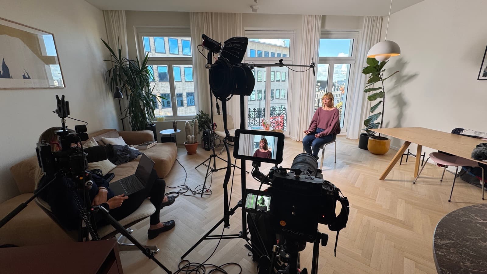 A bright flat lit for an interview, camera and monitor in the foreground and the contributor framed up by the window