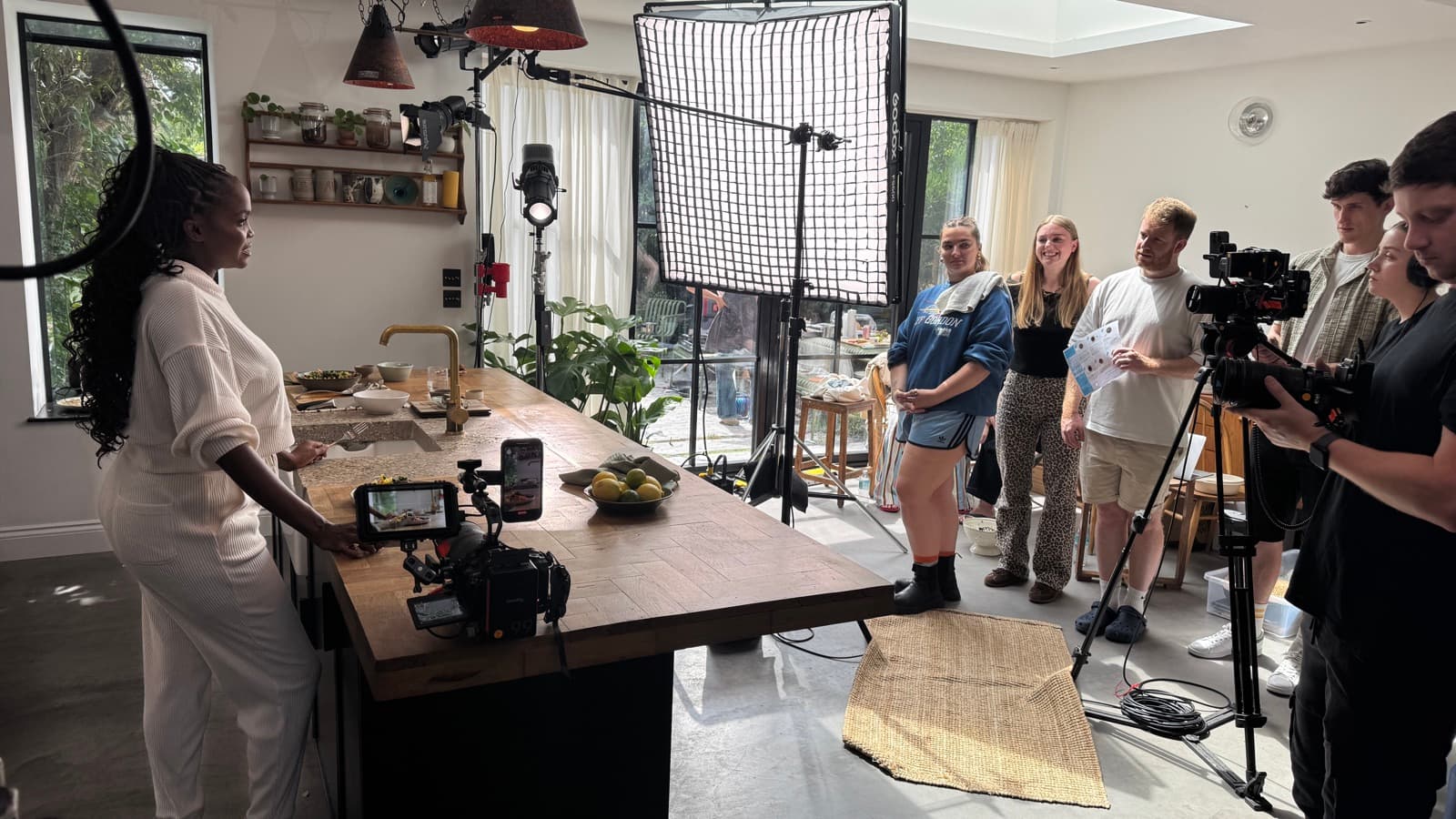 A kitchen set mid-shoot, a large softbox over the island and the room watching from behind the camera