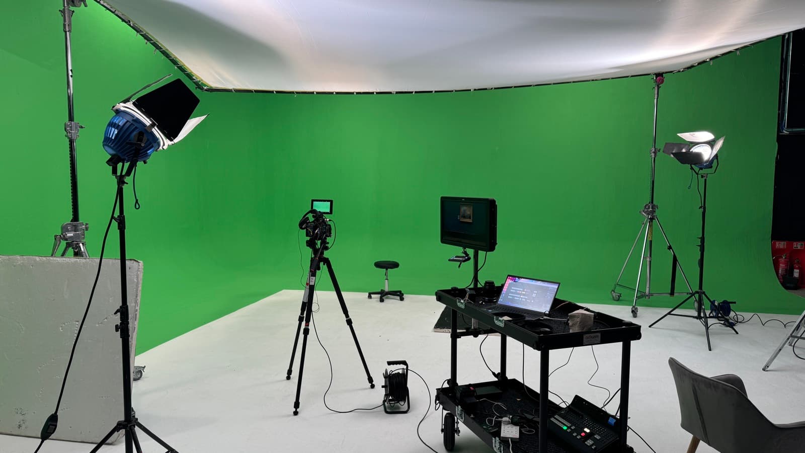 A green-screen studio lit and rigged, camera, monitor and playback cart in position before anyone is on set