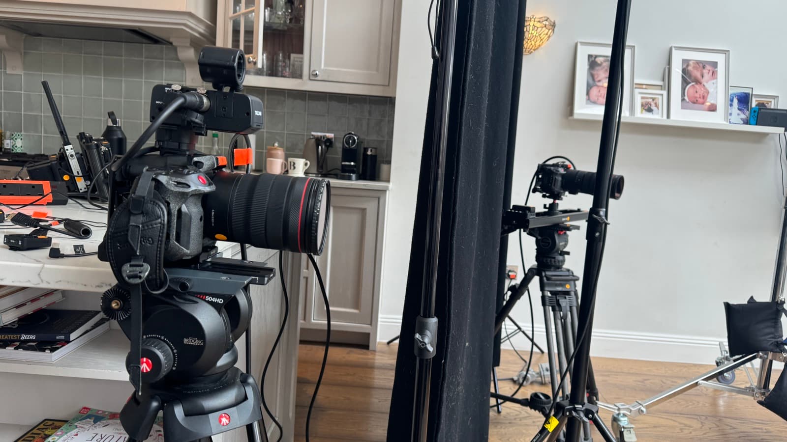 Two cameras built and standing in a kitchen between set-ups, lighting stands still in position
