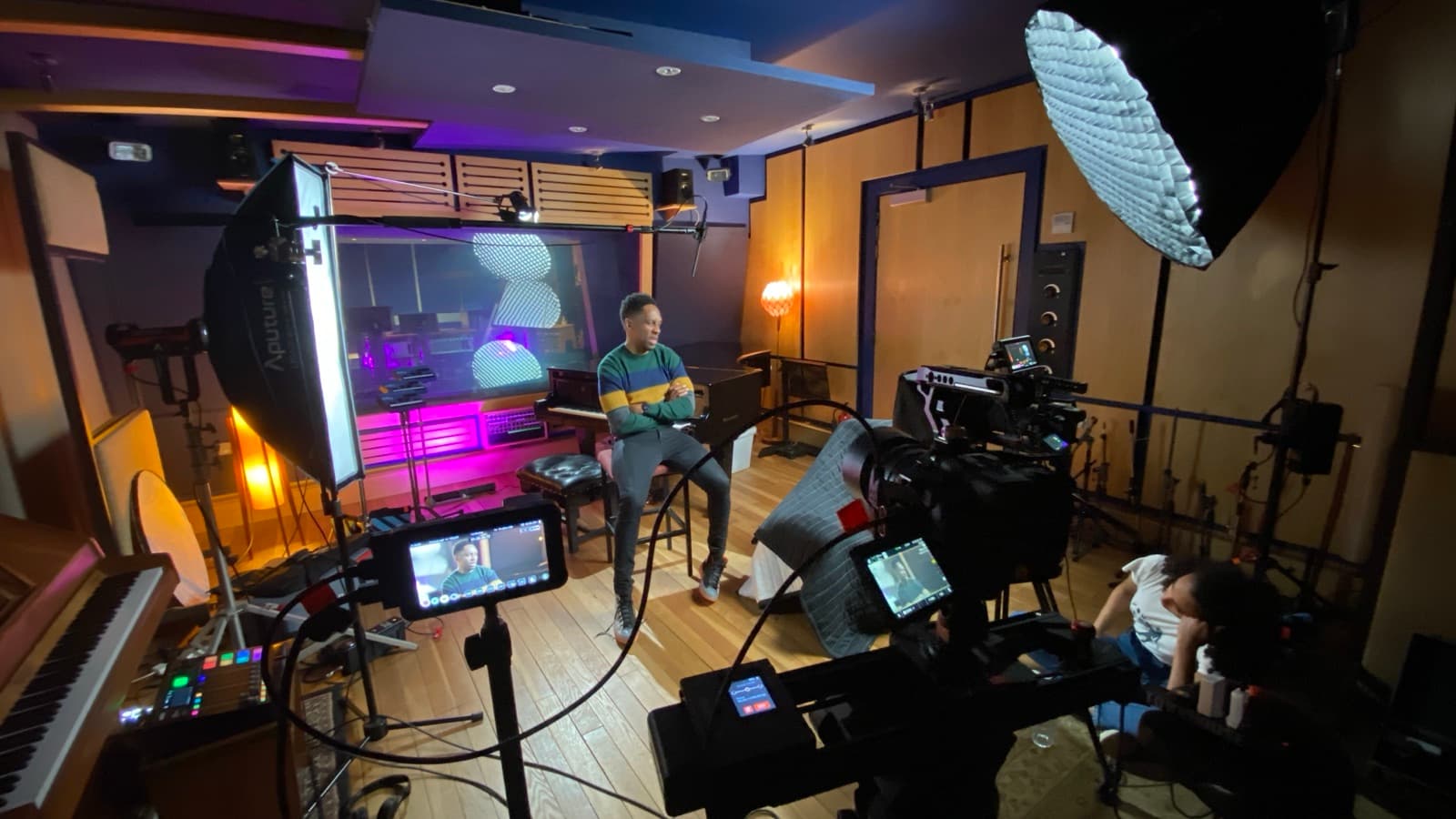 A live room lit magenta, large softbox above and two cameras on the performer
