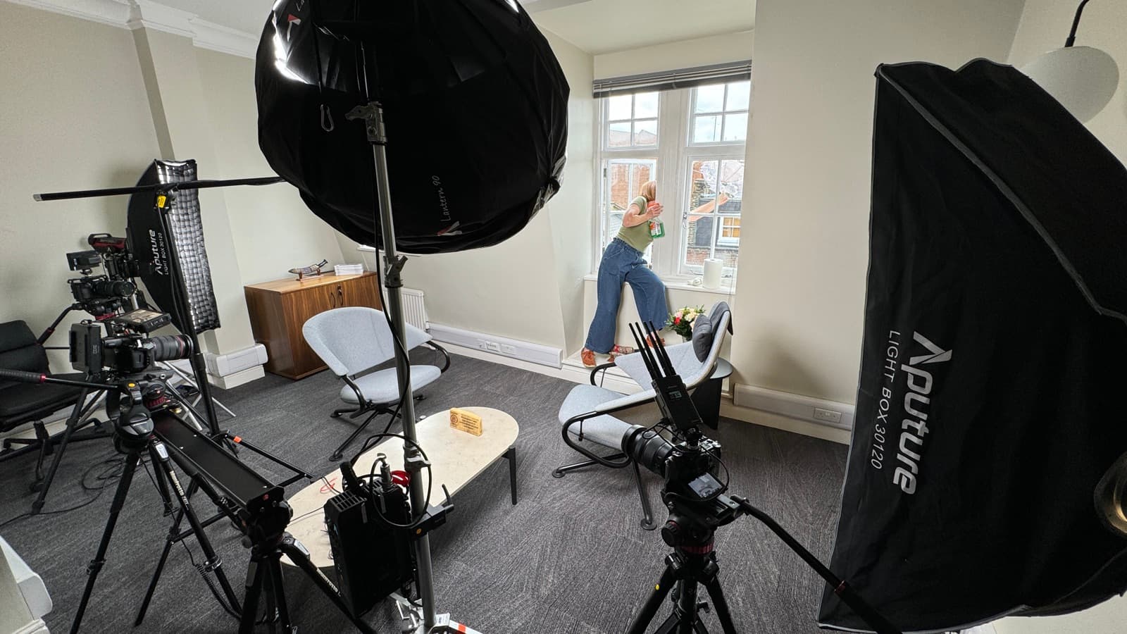 A living room rigged for a shoot, a dome light overhead and a large softbox flagging the window
