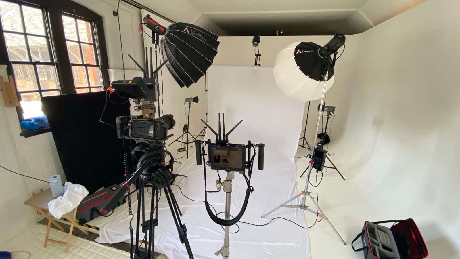 A studio corner rigged with a large softbox and a second head, camera and gimbal standing by