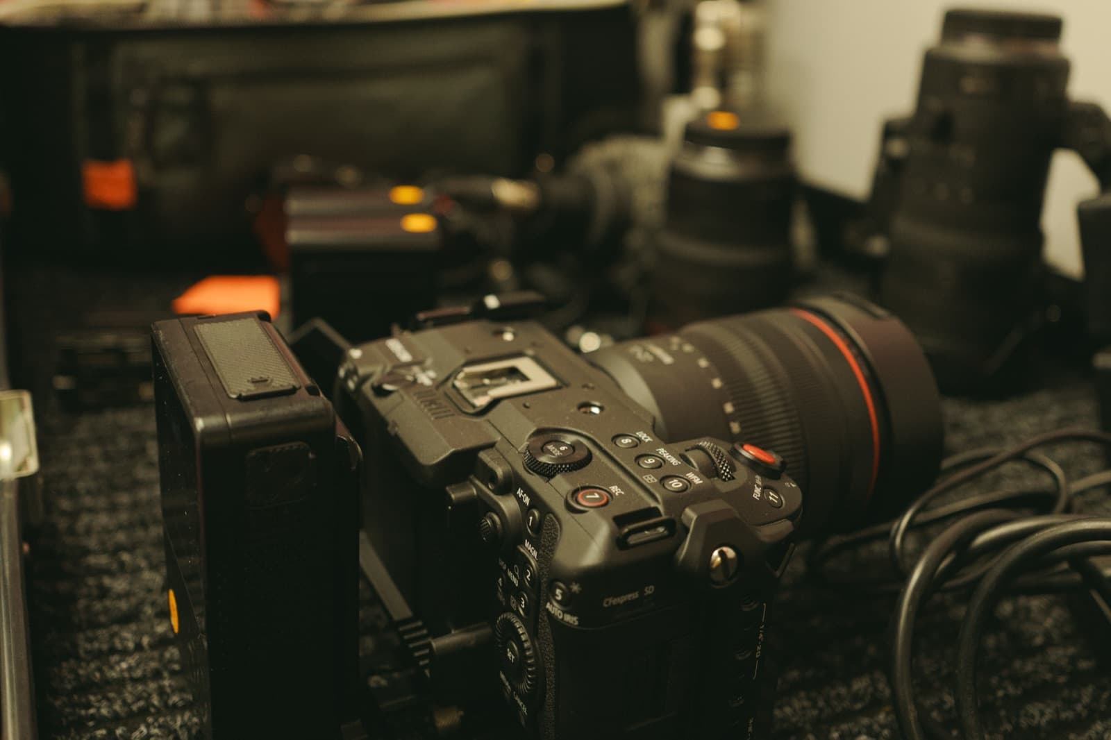 A cinema camera built up and set down on gravel between set-ups, cases and cable behind it