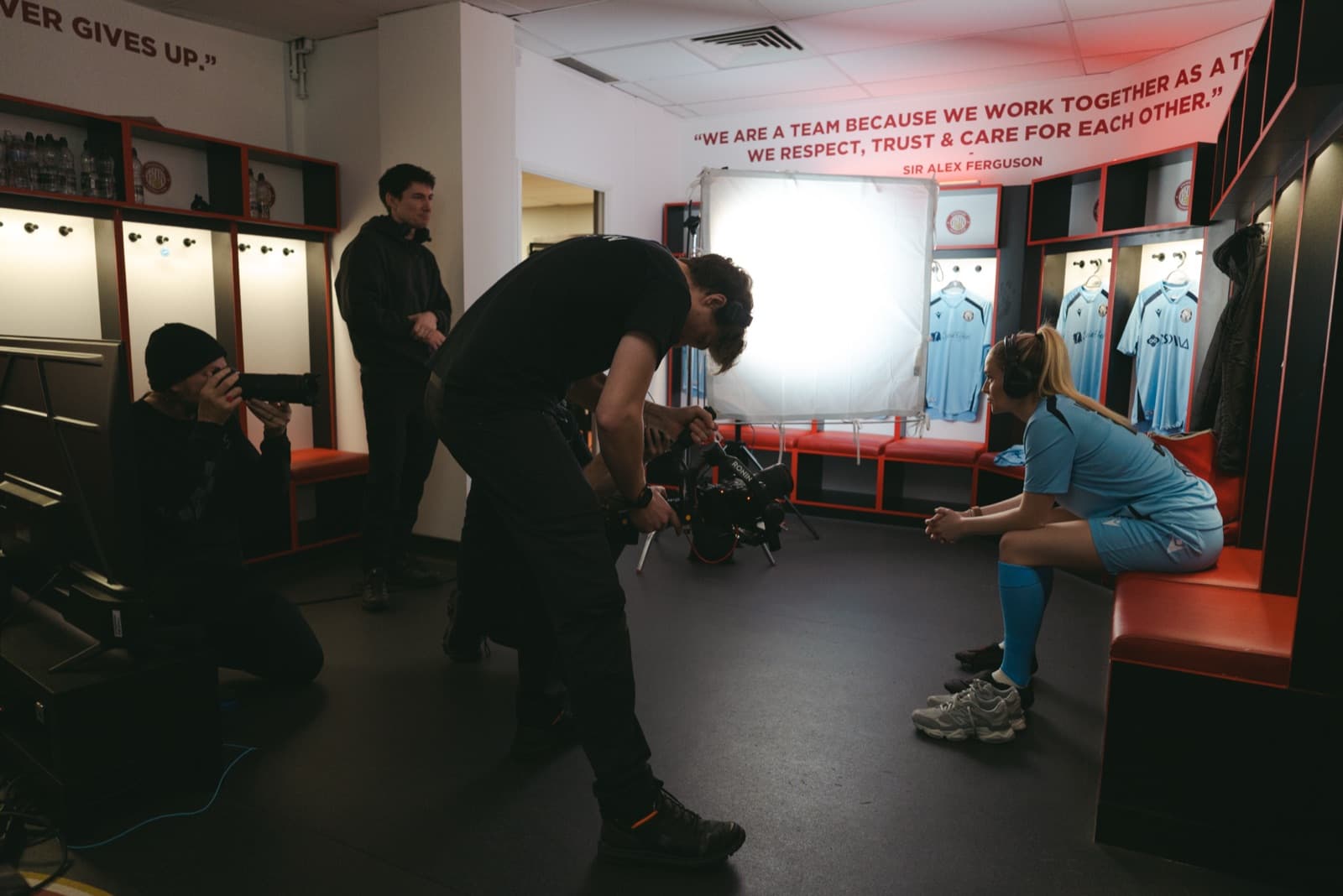The full unit working in a dressing room — camera, sound and a light against the kit pegs