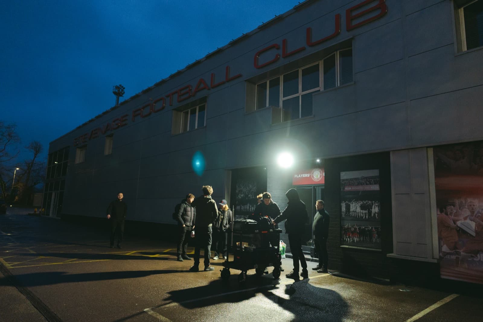 The unit outside a football club after dark, a single hard source lighting the frontage