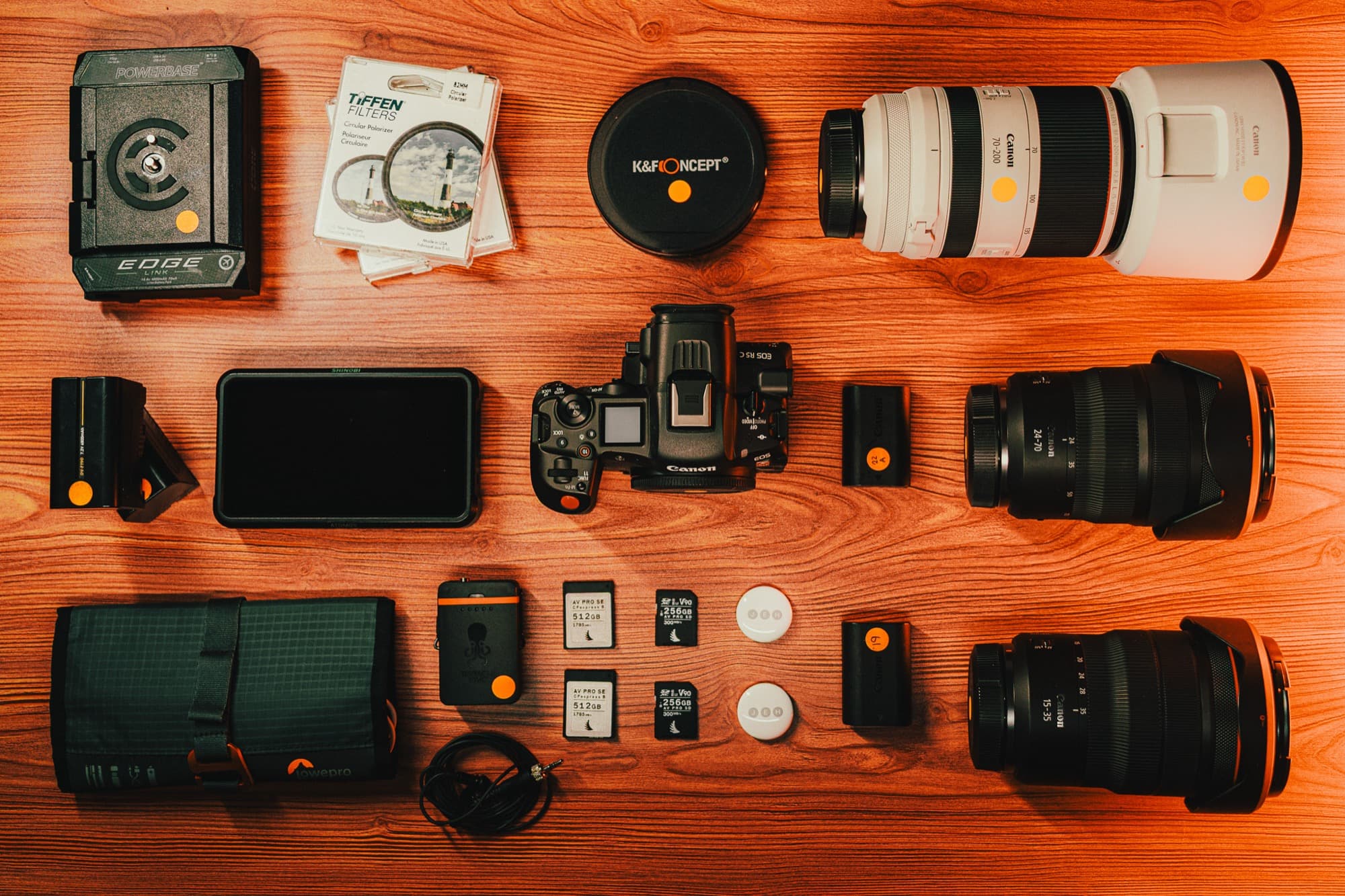 Camera bodies, lenses, batteries and media laid out on a workbench before a shoot