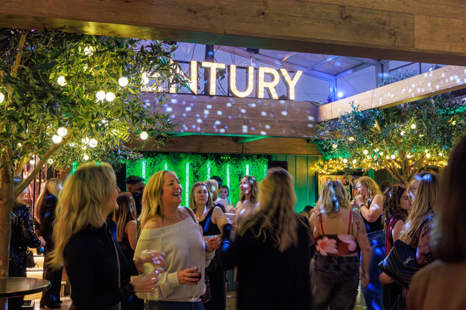 The Century sign above a full room at a members' night