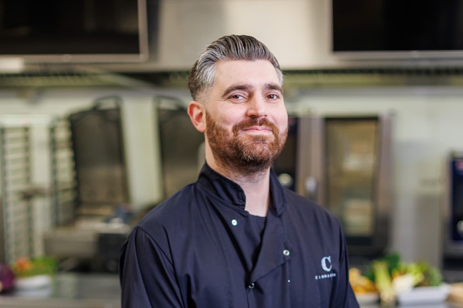 A Cinnamon chef in branded whites, photographed in the competition kitchen