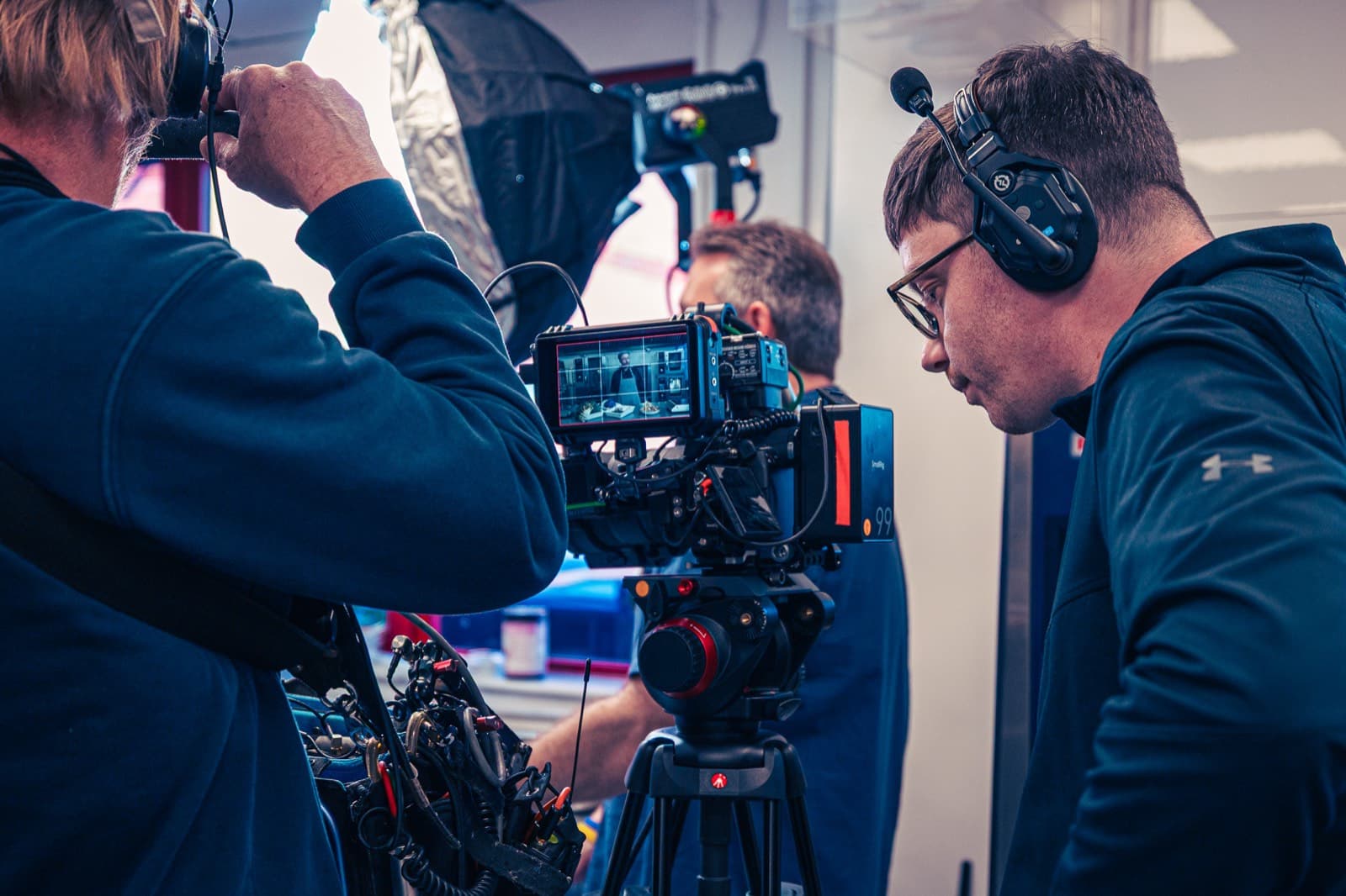 Two of the crew at the camera, a chef framed on the monitor between them