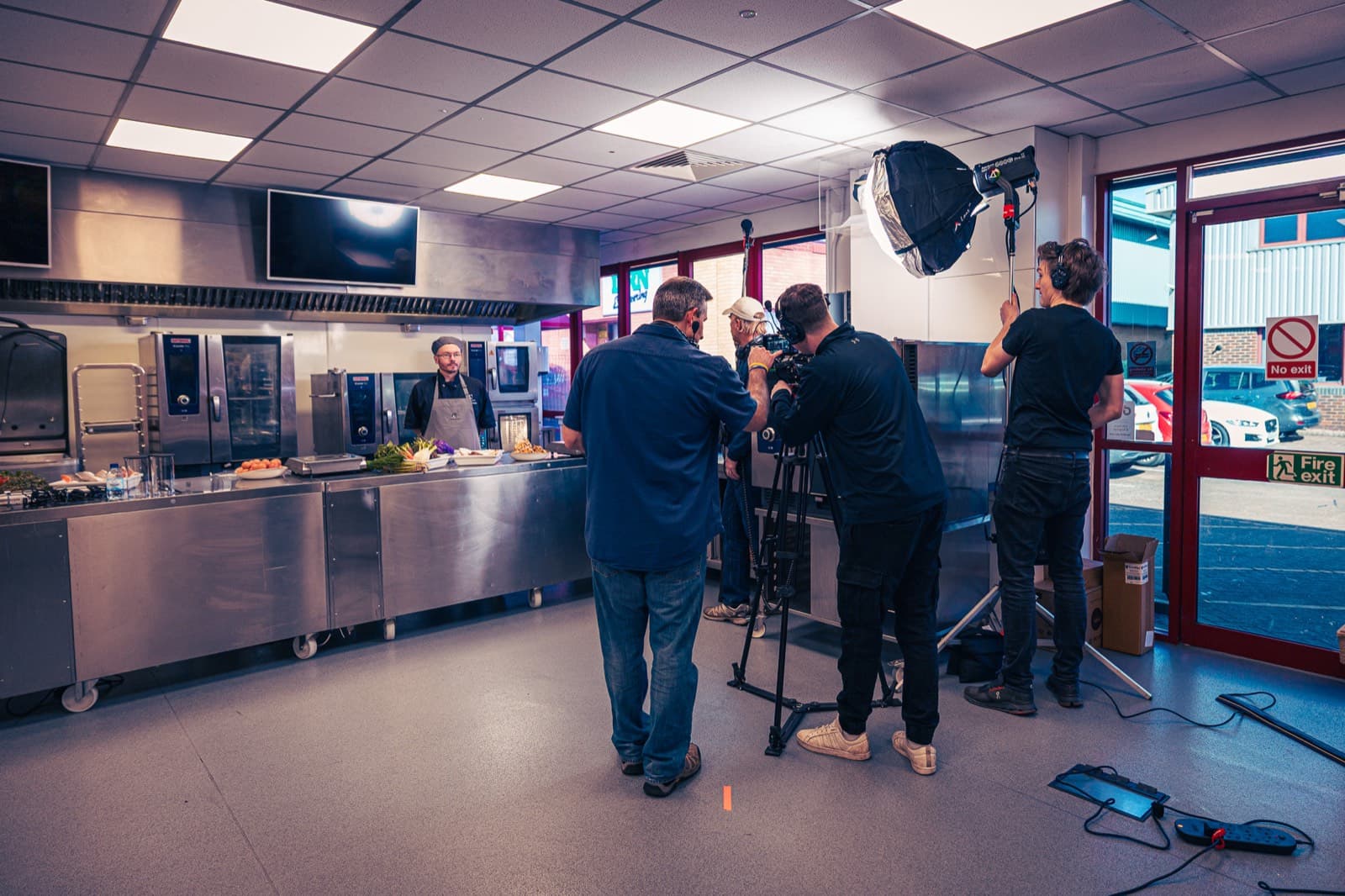 The full unit in the competition kitchen — softbox, camera on sticks and boom, four crew, one chef at the pass